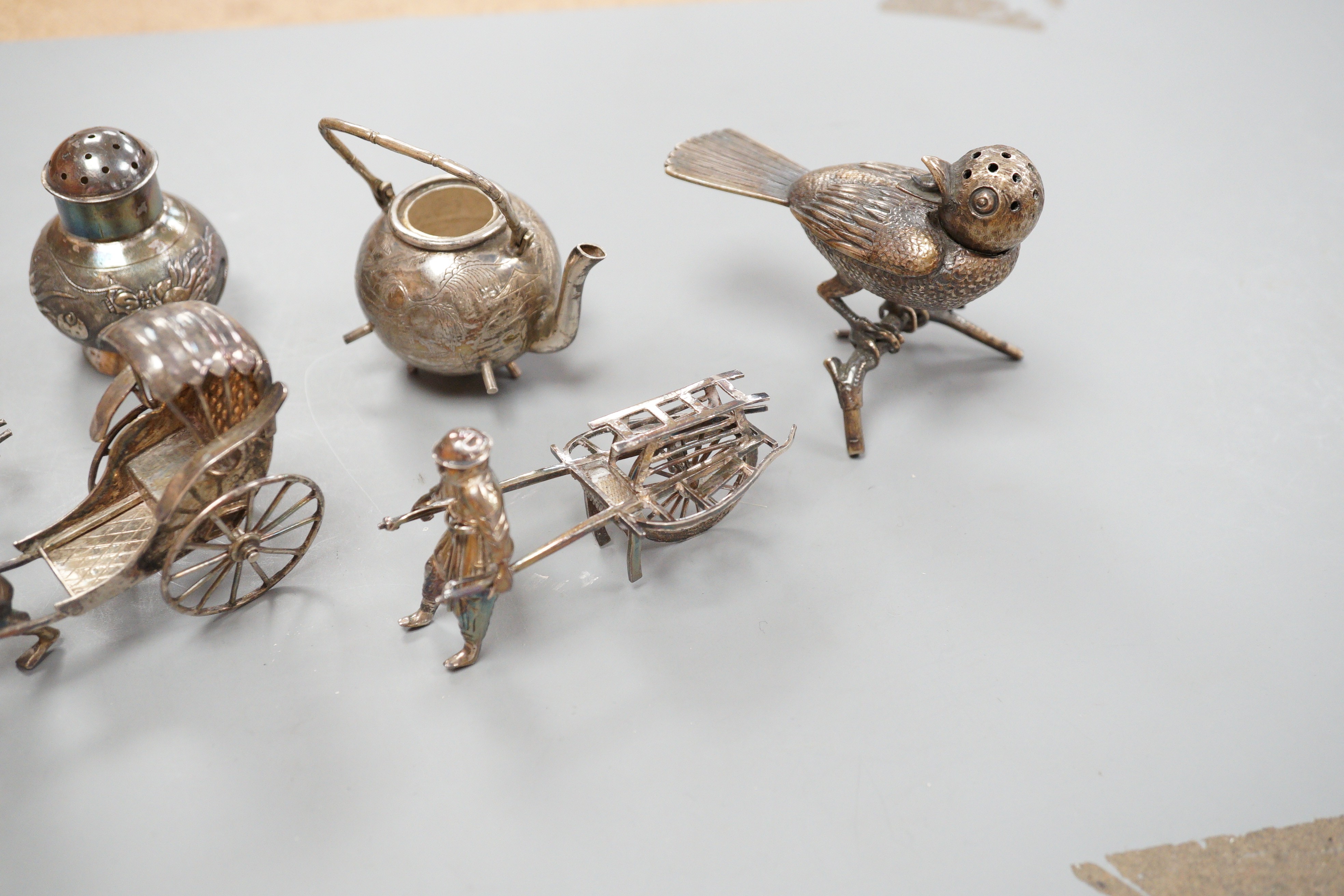 Six assorted miniature white metal items including a Chinese tea kettle on stand (lacking lid), height 93mm, maker CS, a similar rickshaw with driver, maker CH, a Chinese condiment and three other items.